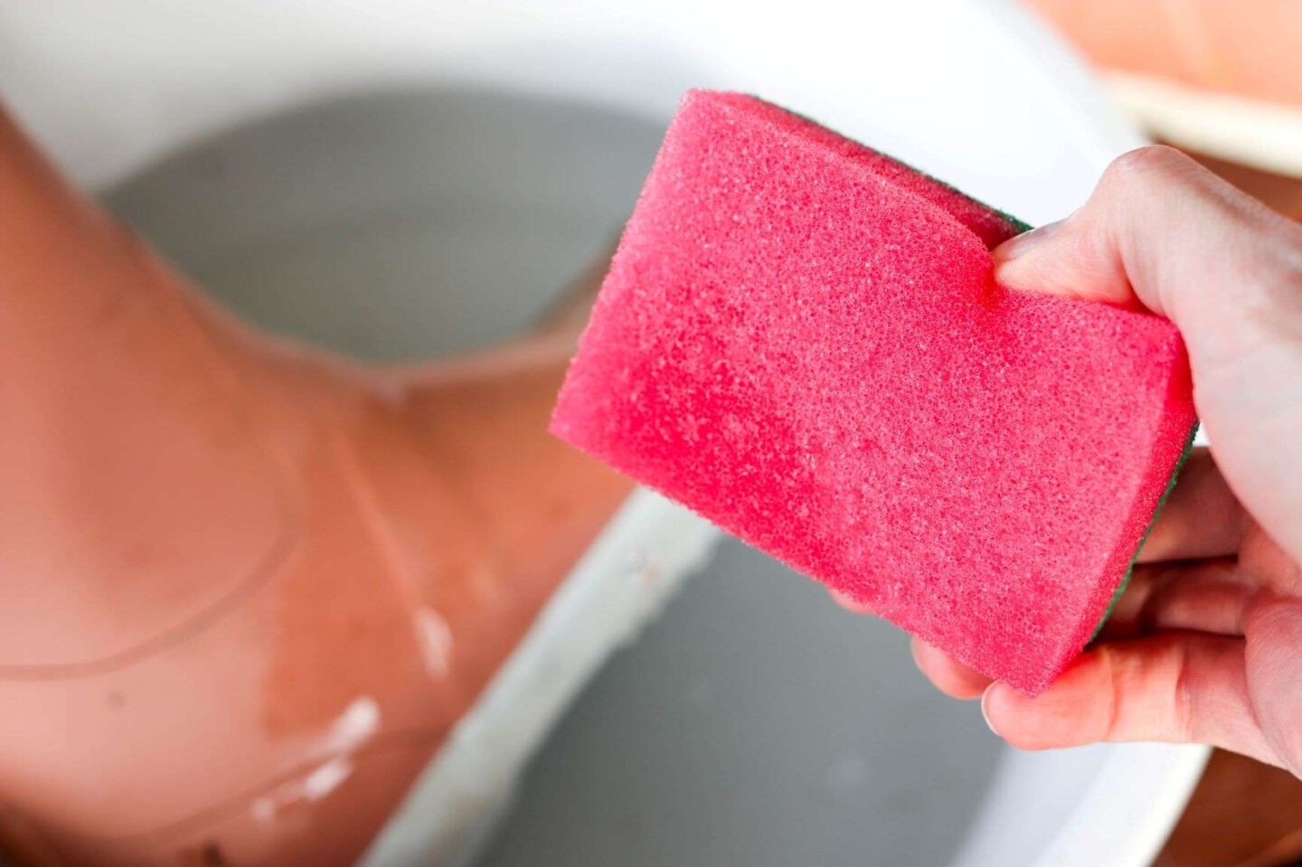 Kumisaappaiden pesu pehmeällä sienellä.