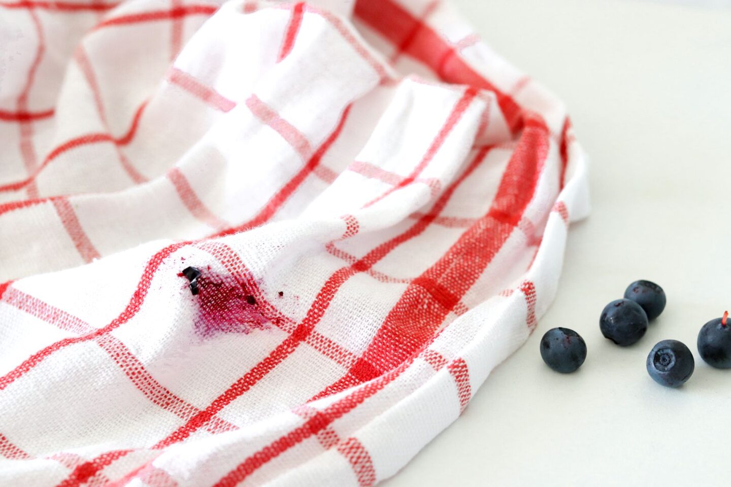 Mustikkatahra pyyhkeessä ja tuoreita mustikoita