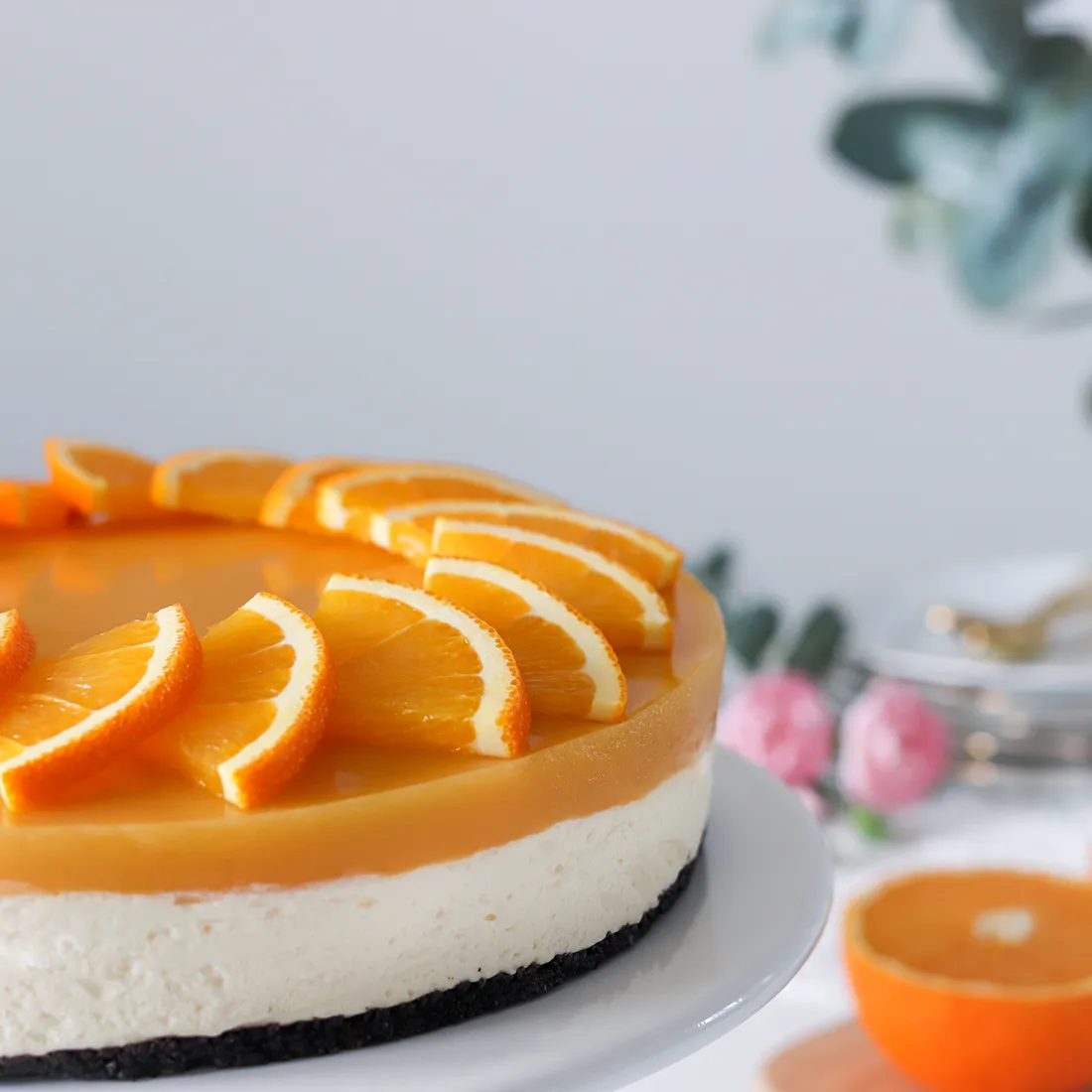 Appelsiinijuustokakku ja puolikas appelsiini, josta on tehty koristeita kakun päälle.