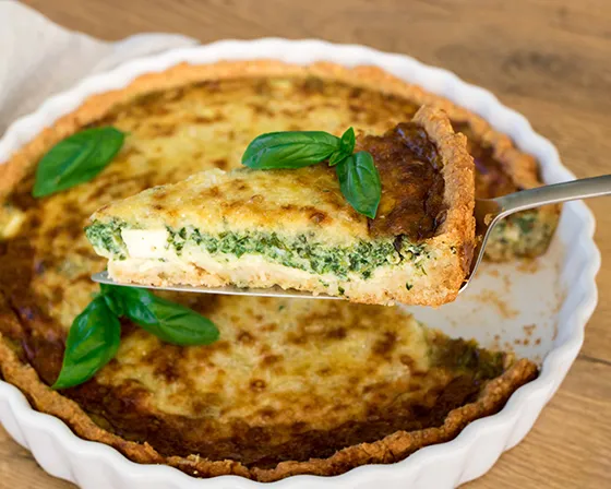 Feta-pinaattipiirakka, josta on nostettu pala kakkulapion päälle.