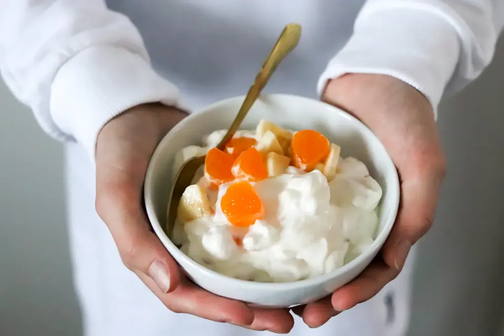 Hedelmillä koristeltu rahka valkoisessa kulhossa.