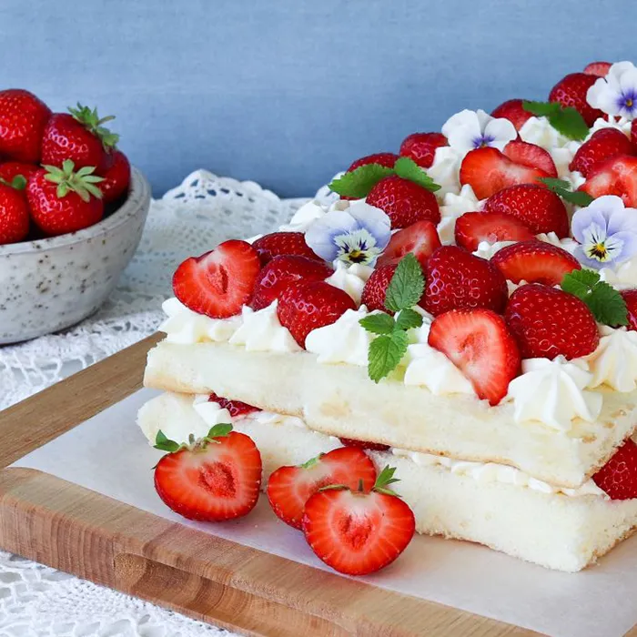 Helppo mansikkakakku puisen leikkuulaudan päällä.