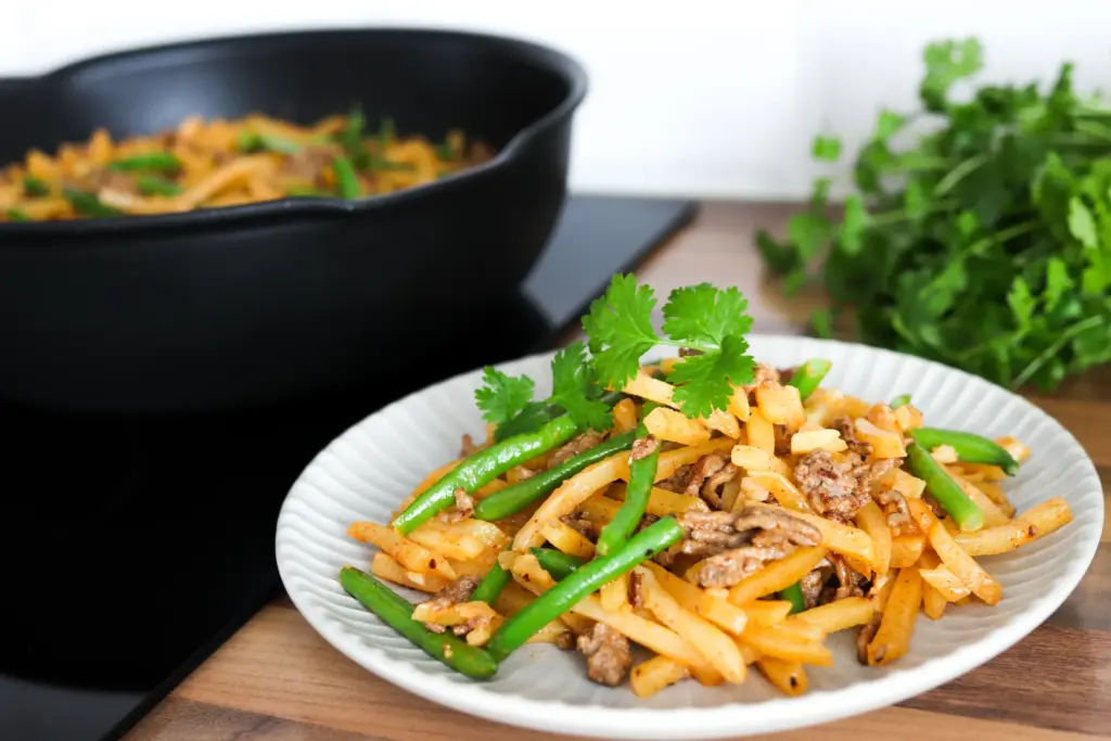 Pannulla paistettua jauhelihakiusausta lautasella korianterin lehdillä koristeltuna.