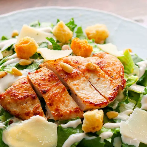 Kana-caesarsalaatti, jonka päällä on krutonkeja.