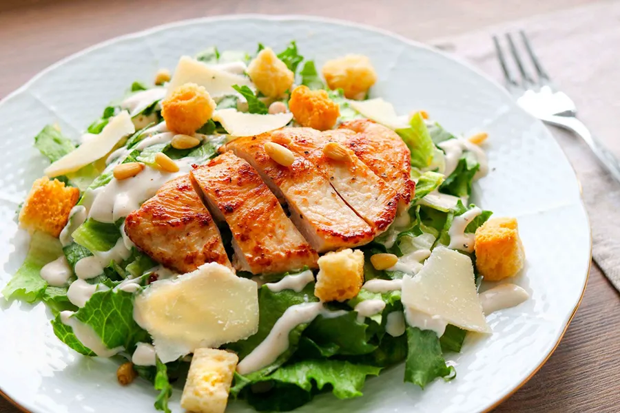 Kana-caesarsalaatti, jonka päällä on paistettu ja viipaloitu broilerin file.