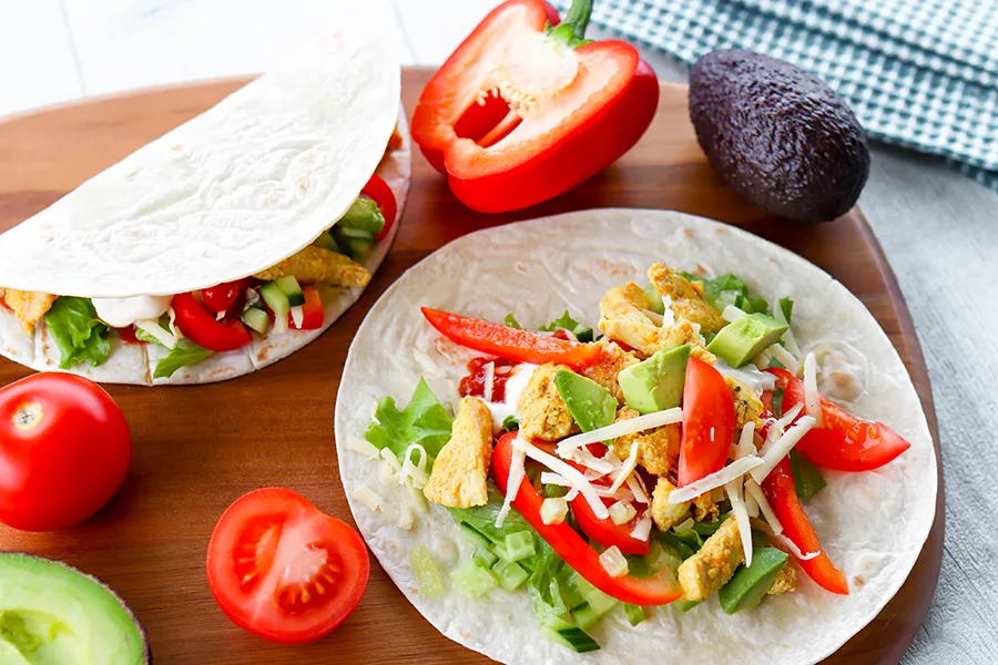 Tortilla kanan ja kasvisten kera leikkuulaudalla.