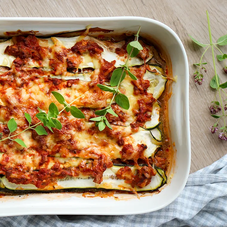 Kesäkurpitsalasagne, joka on koristeltu tuoreella oreganolla.