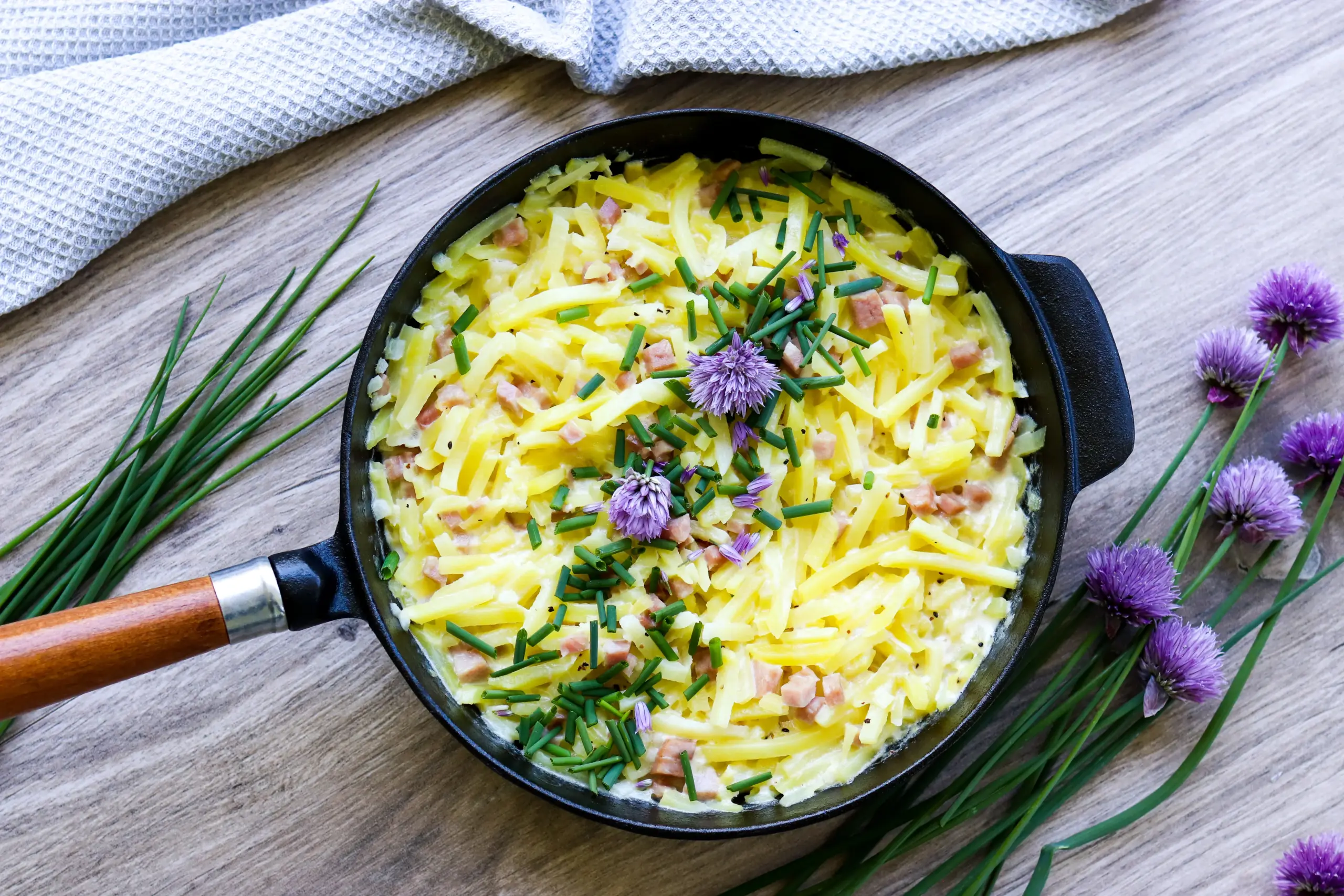 Kinkkukiusausta valurautaisella pannulla ruohosipulilla koristeltuna.