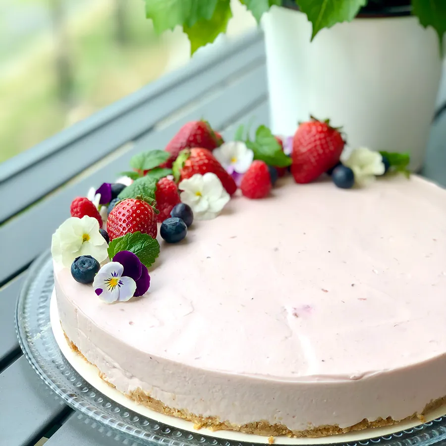 Kuningatar-juustokakku, jonka päällä on tuoreita marjoja.