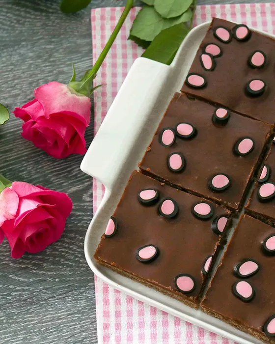 Lakritsi-mokkapalat paloiksi leikattuna pinkkien ruusujen vieressä.
