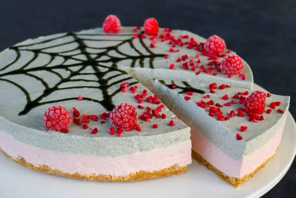 Lakritsi-vadelmajuustokakku, jonka pinnalle on tehty halloweeniin sopiva musta hämähäkin seitti.