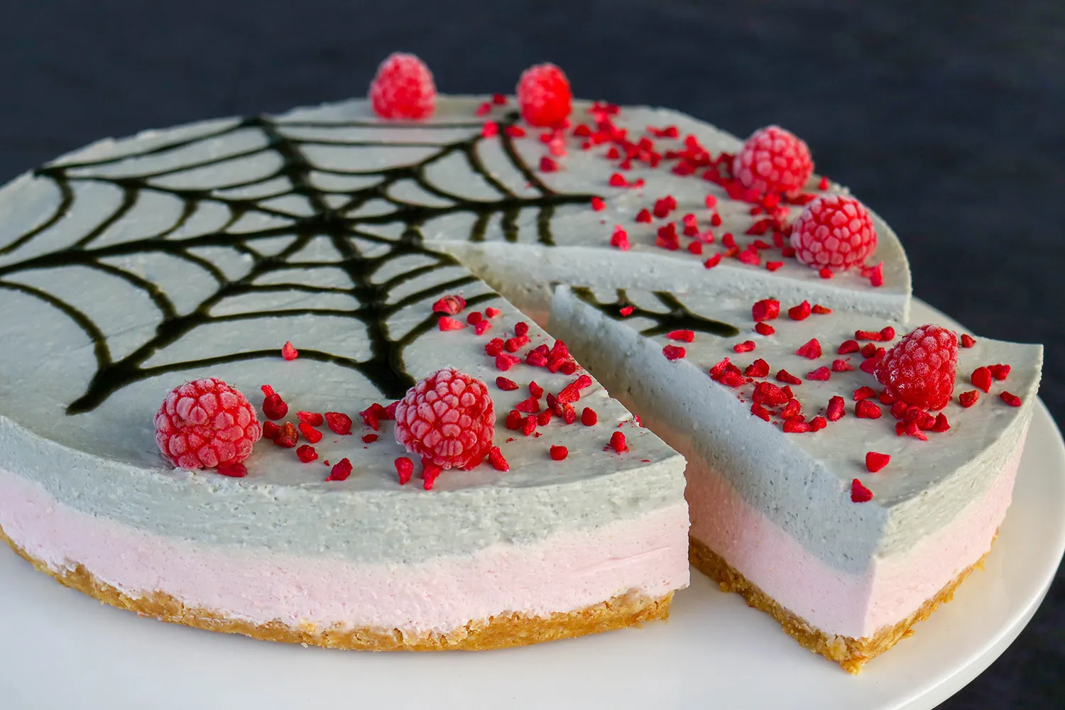 Lakritsi-vadelmajuustokakku, jonka pinnalle on tehty halloweeniin sopiva musta hämähäkin seitti.