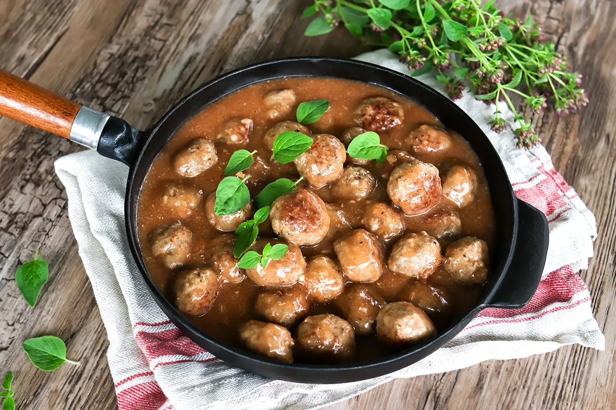 Lihapullakastike paistinpannulla tuoreella oreganolla koristeltuna.