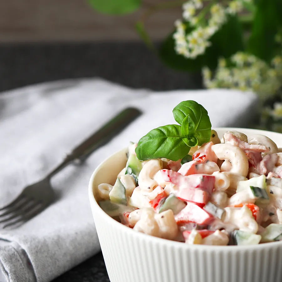 Makaronisalaatti, jonka päällä on basilikaa.