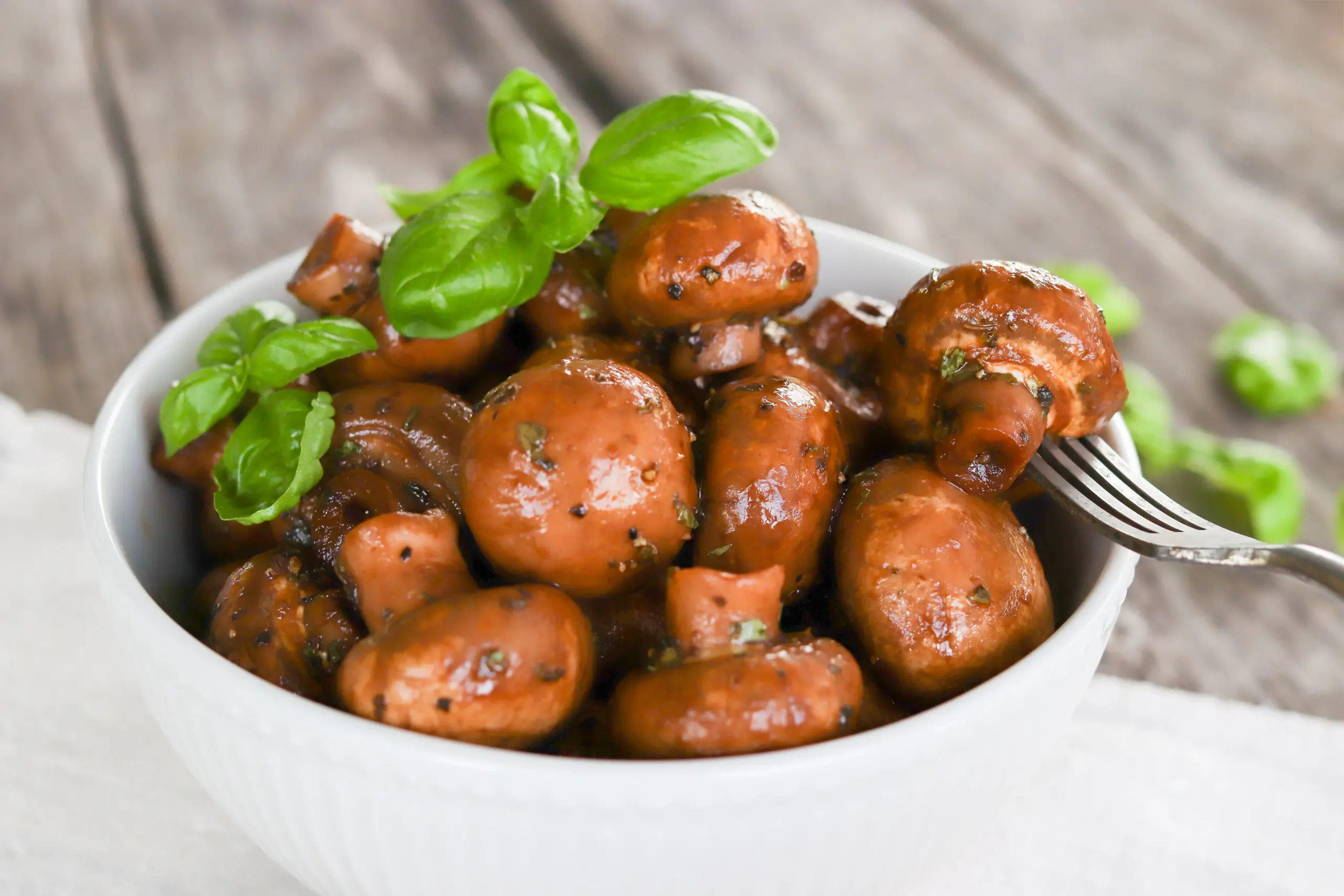 Marinoidut herkkusienet tuoreella basilikalla koristeltuna.