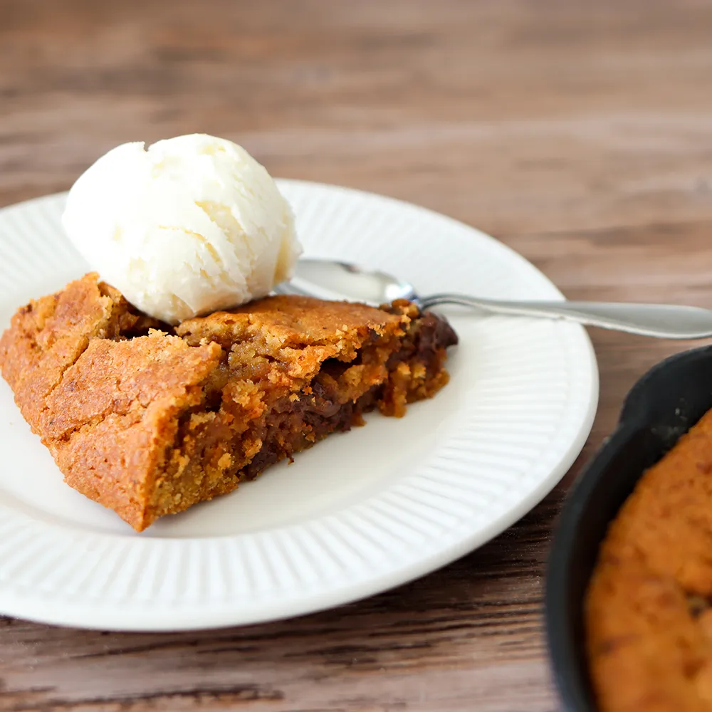 Pannukeksi valkoisen jäätelöpallon kanssa lautasella.