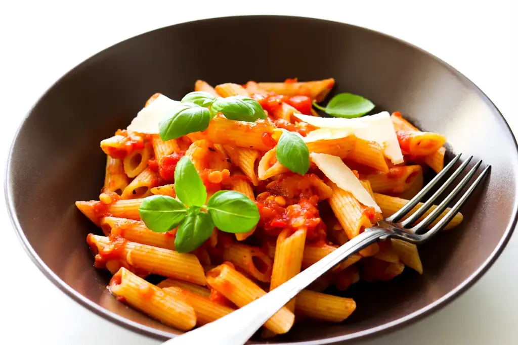 Pasta arrabbiata ruskealla lautasella.