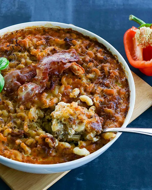 Pekoni-makaronilaatikko, jonka päällä on pari paistettua pekoniviipaletta.
