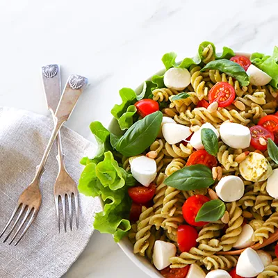Pesto-pastasalaatti isossa kulhossa sekä kaksi kaunista haarukkaa.
