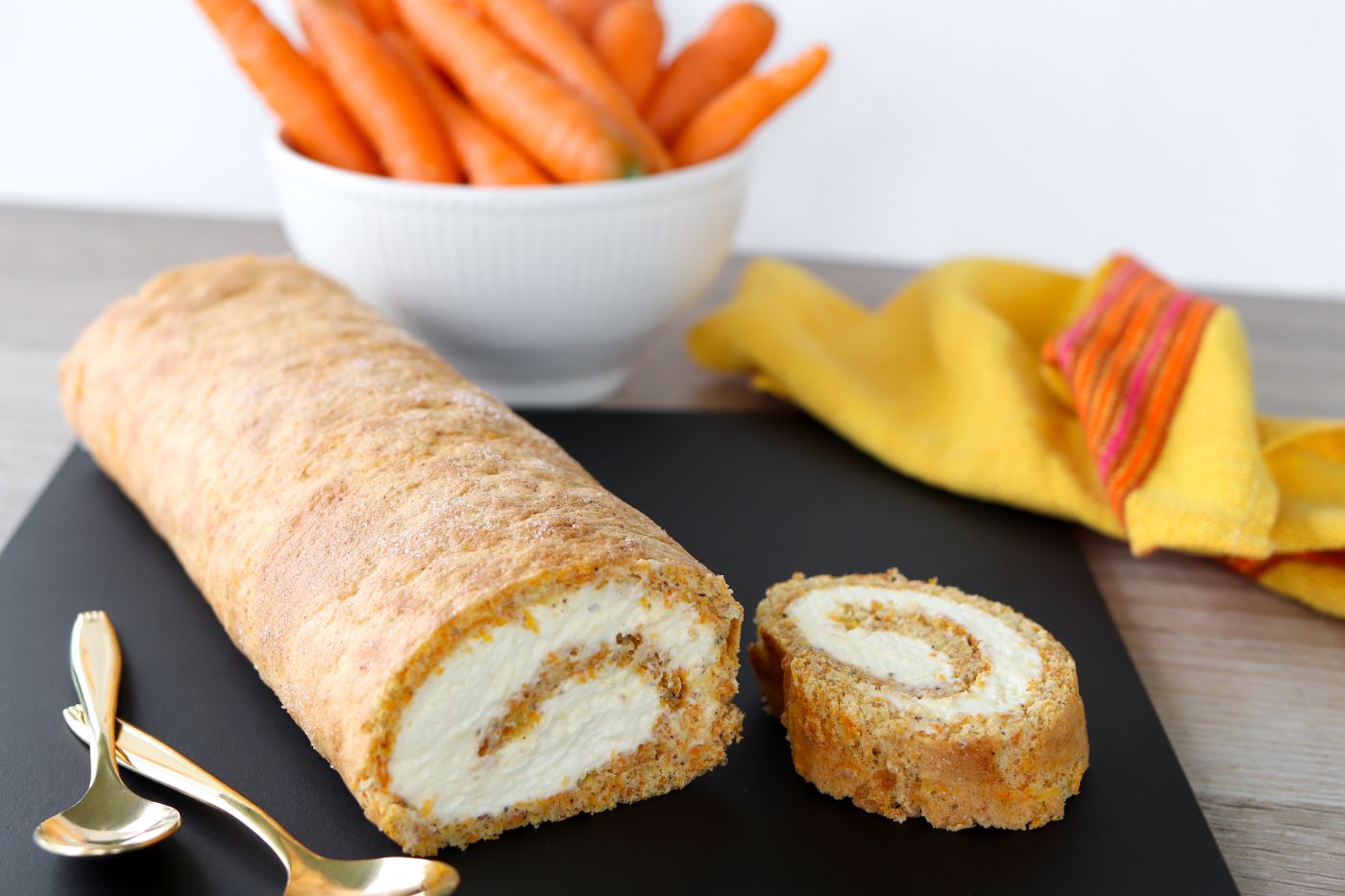 Porkkanakakun makuista kääretorttua mustalla leikkuulaudalla