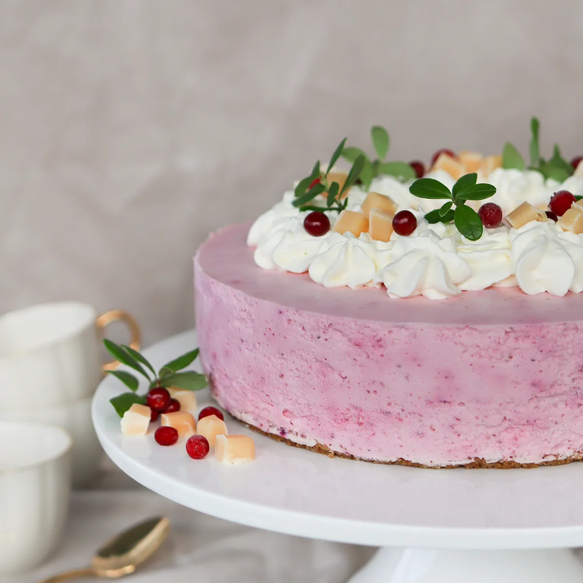 Puolukkajuustokakku, jonka pinnalla on kermavaahtoa ja koristeita.