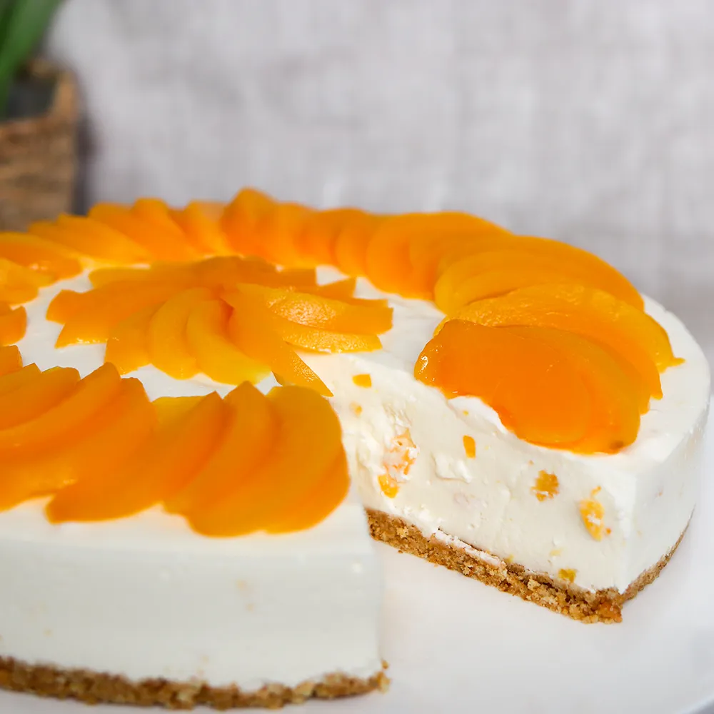 Rahkakakku koristeltuna säilötyllä persikalla.