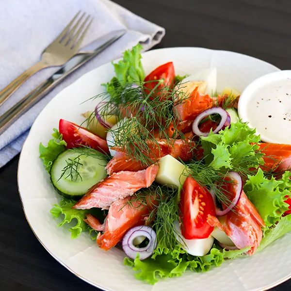 Savulohisalaatti kauniilla valkoisella lautasella.