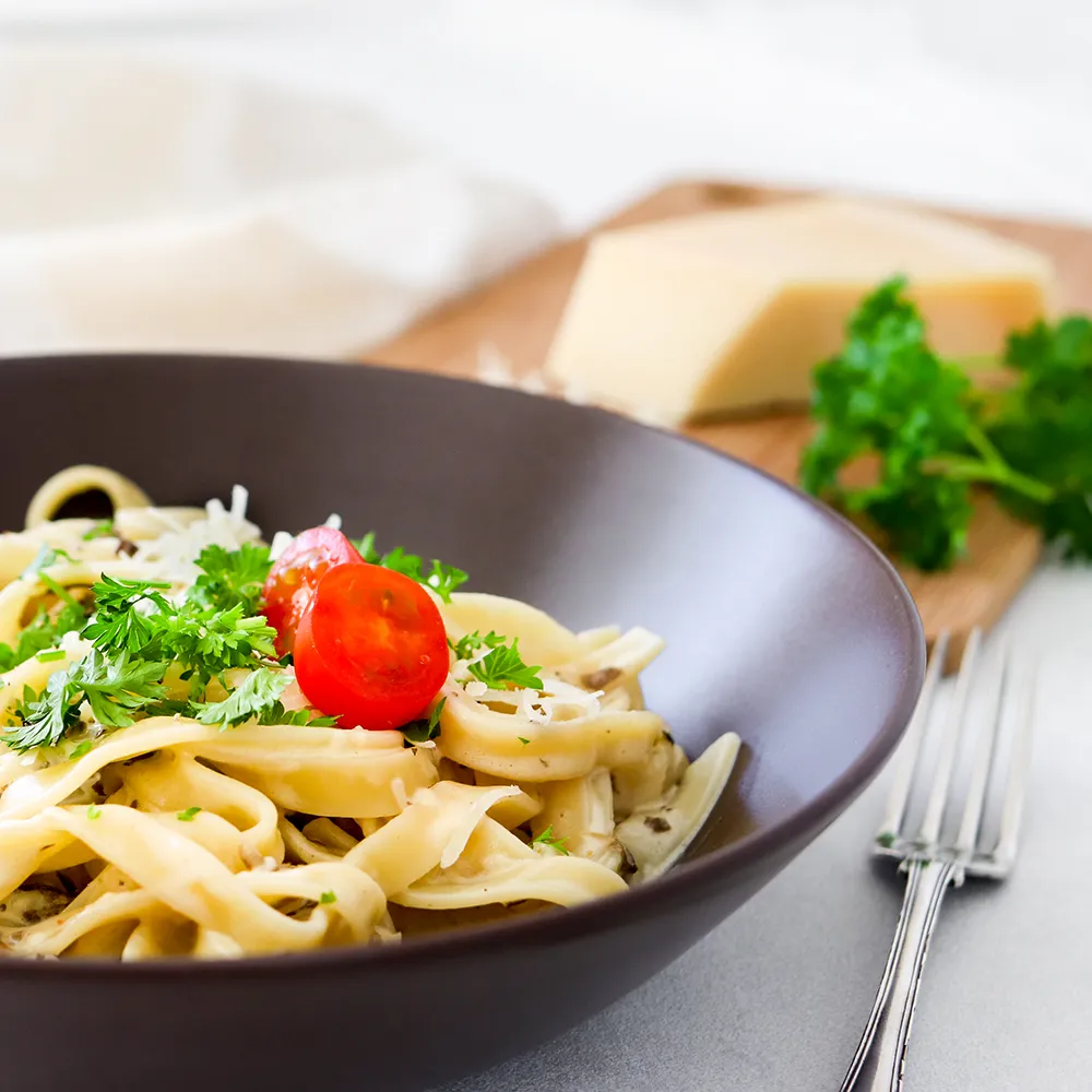 Sienipasta lautasella minitomaatilla koristeltuna.