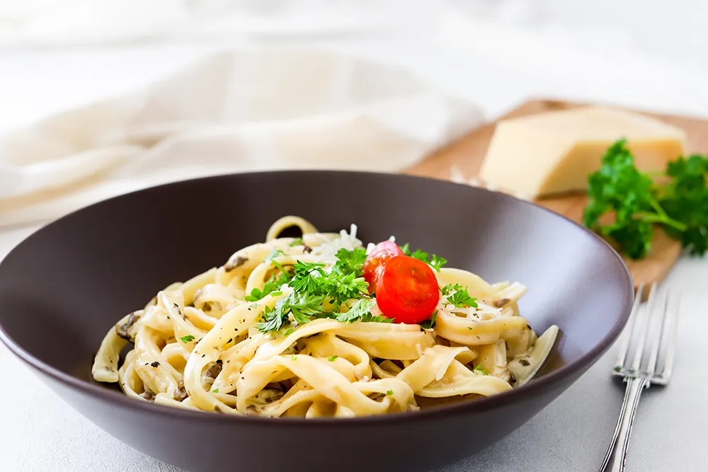 Sienipasta tomaatilla ja persiljalla koristeltuna.