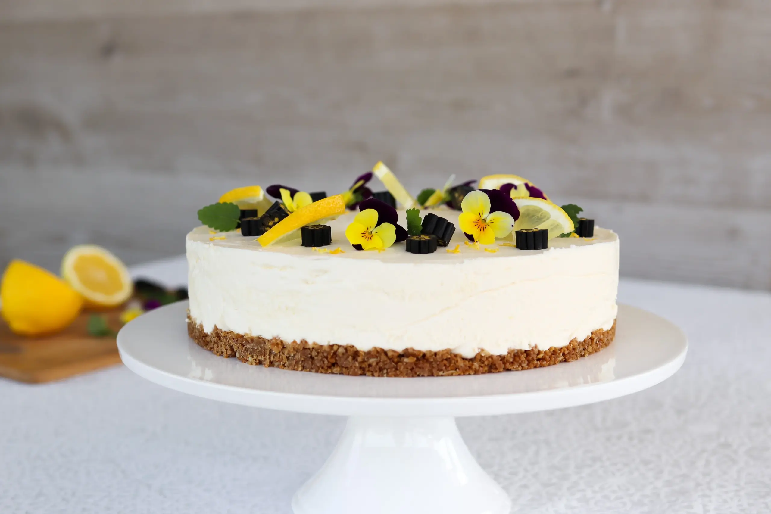 Sitruunajuustokakku lakuilla ja orvokeilla koristeltuna.