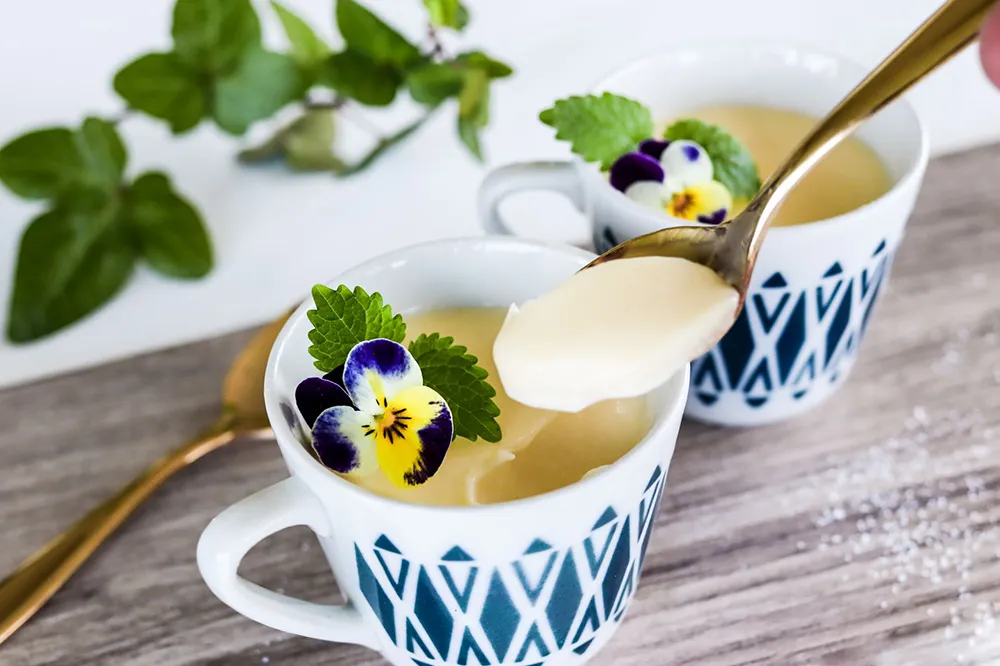 Sitruunaposset pienissä kahvikupeissa orvokeilla koristeltuna.