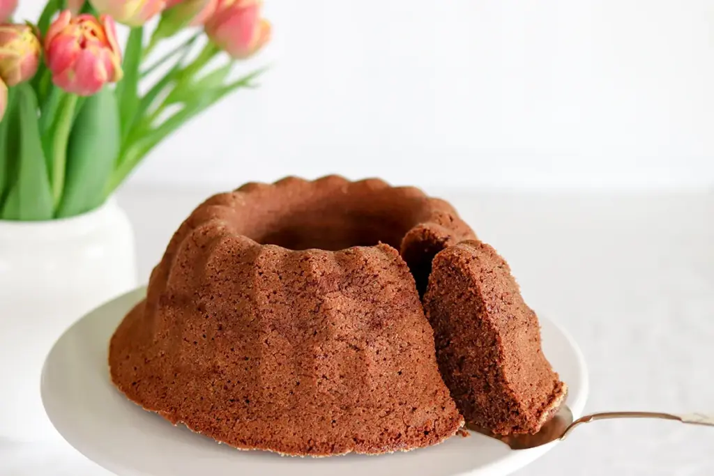 Suklaakahvikakku ja tulppaaneita maljakossa.