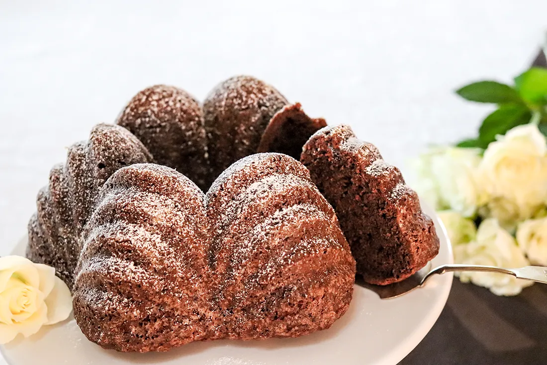 Suklainen piimäkakku valkoisten ruusujen vierellä.