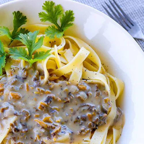 Suppilovahverokastike tagliatelle-pastan kanssa syvällä lautasella.