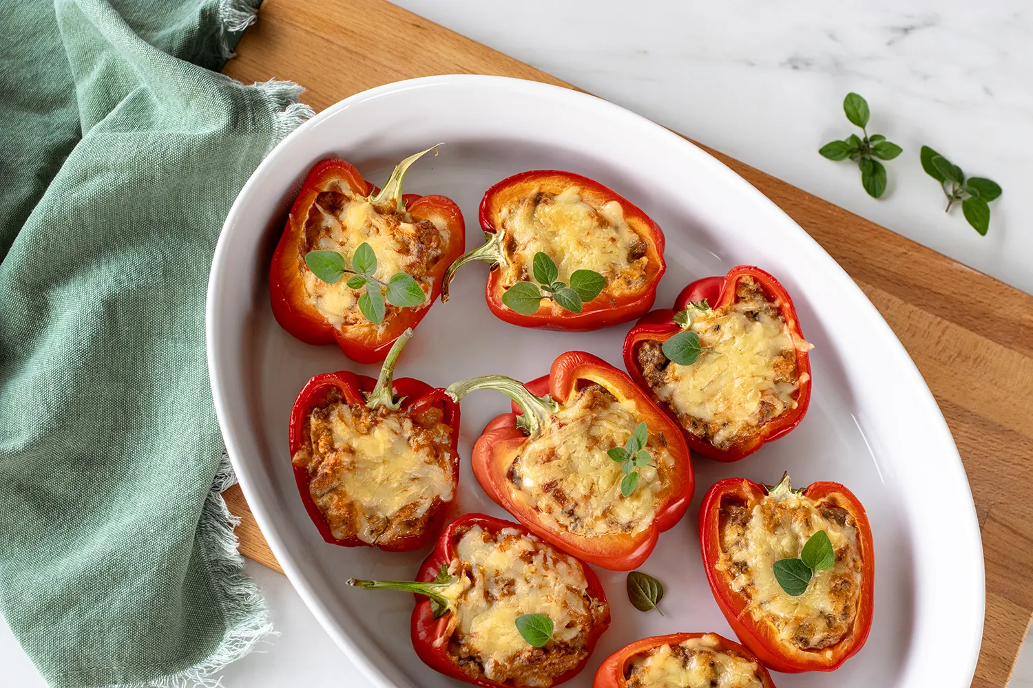 Täytetyt paprikat valkoisella uunin kestävällä vuoalla.
