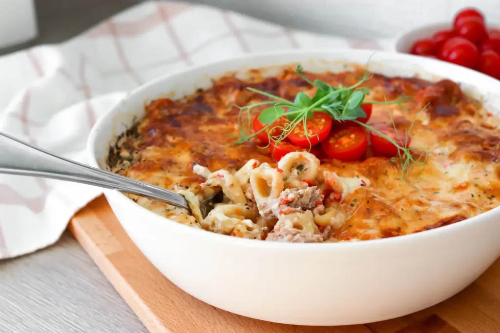 Tonnikalapasta uunissa paistamisen jälkeen pienillä tomaateilla ja herneenversoilla koristeltuna.