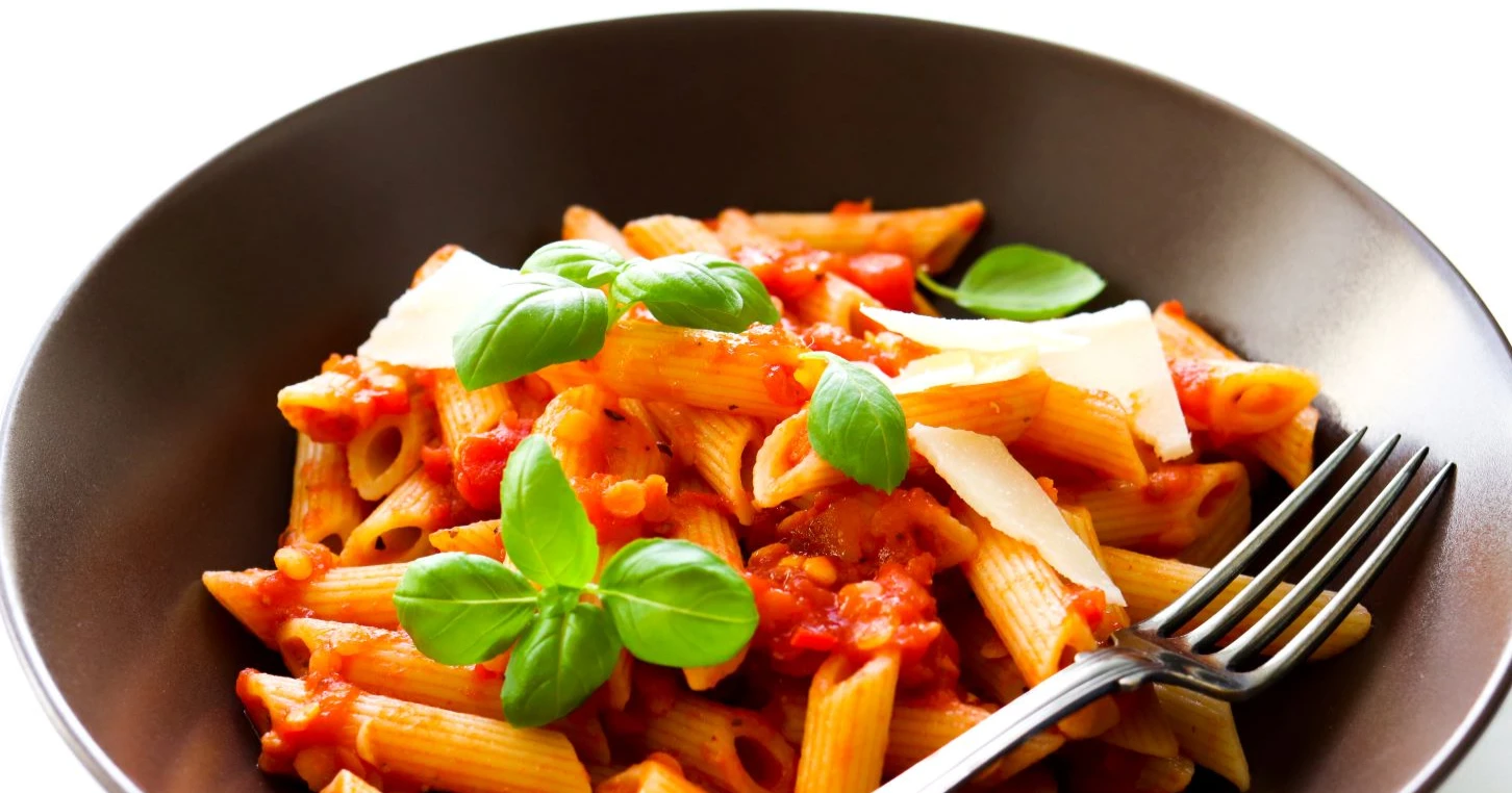 Pasta arrabbiata ruskealla lautasella.