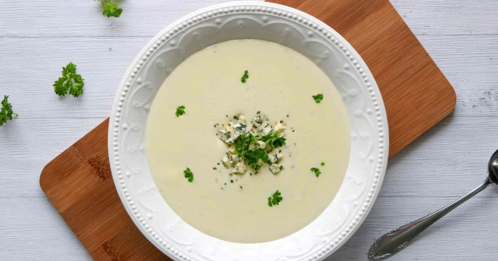 Aurajuustokeitto valkoisella lautasella tuoreella persiljalla koristeltuna.