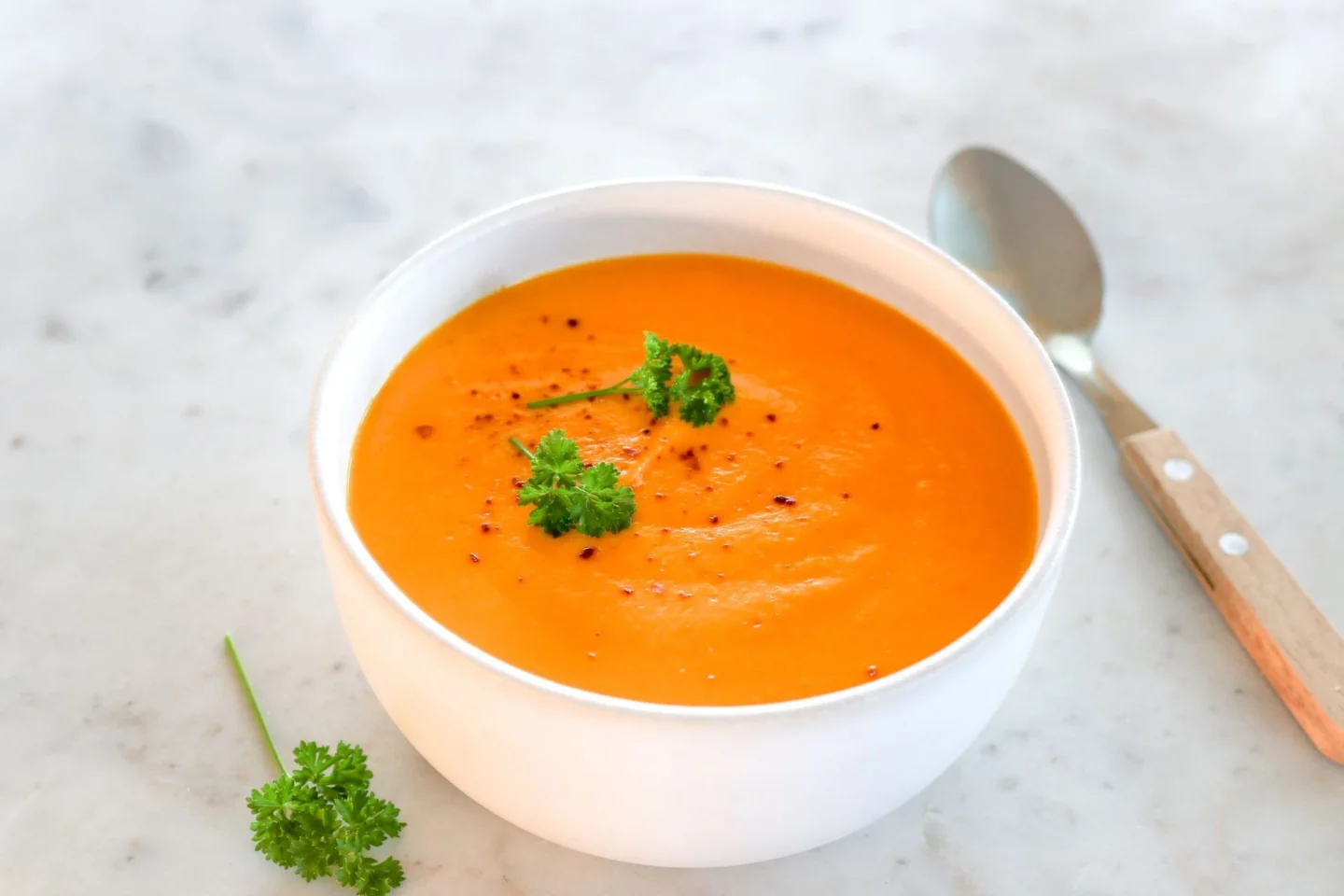 Bataattikeitto valkoisessa kulhossa tuoreella persiljalla koristeltuna.