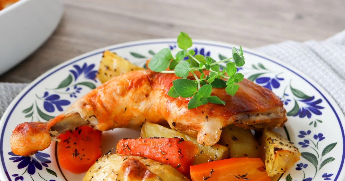 Broilerin koipireisi lautasella perunoiden ja porkkanoiden kera.