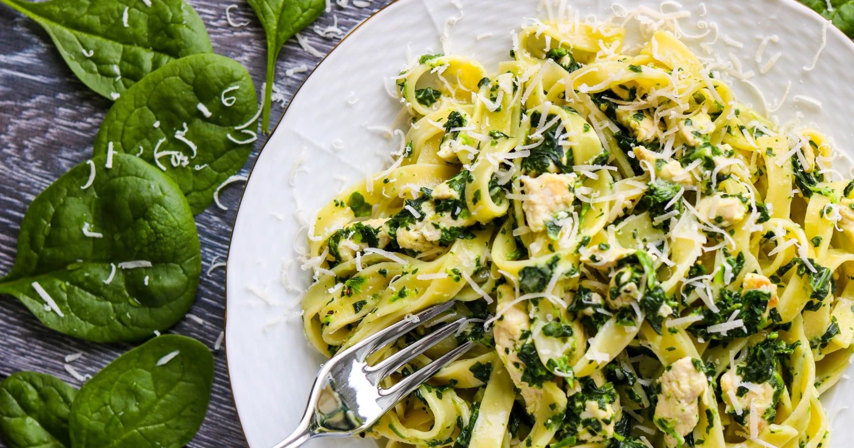 Broileri-pinaattipastaa ja tuoreita pinaatin lehtiä.