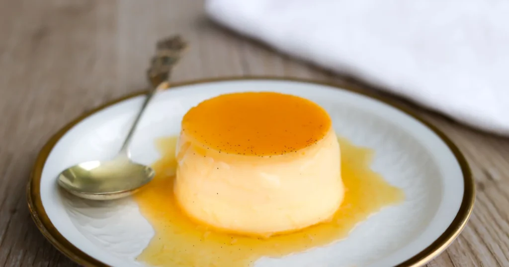 Crème caramel kumottuna kultareunaisella lautasella.