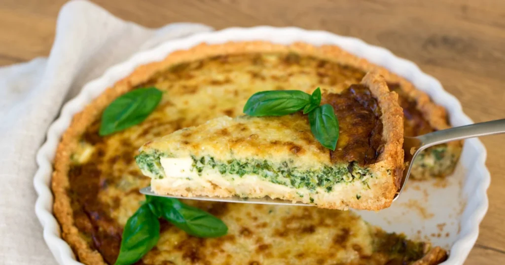 Feta-pinaattipiirakka, josta on leikattu pala kakkulapiolla.