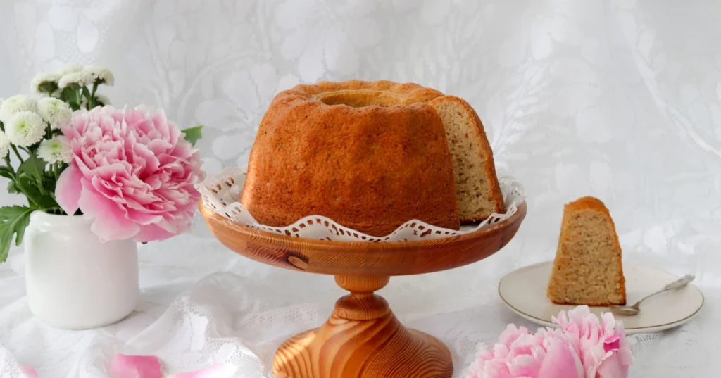 Mehevä gluteeniton kahvikakku puisella, jalallisella tarjoilulautasella.