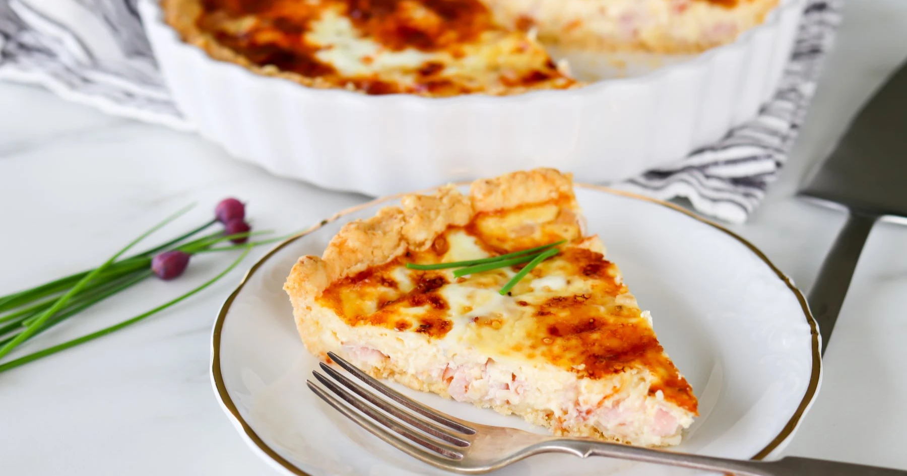 Gluteeniton kinkkupiirakka lautasella ruohosipulilla koristeltuna.