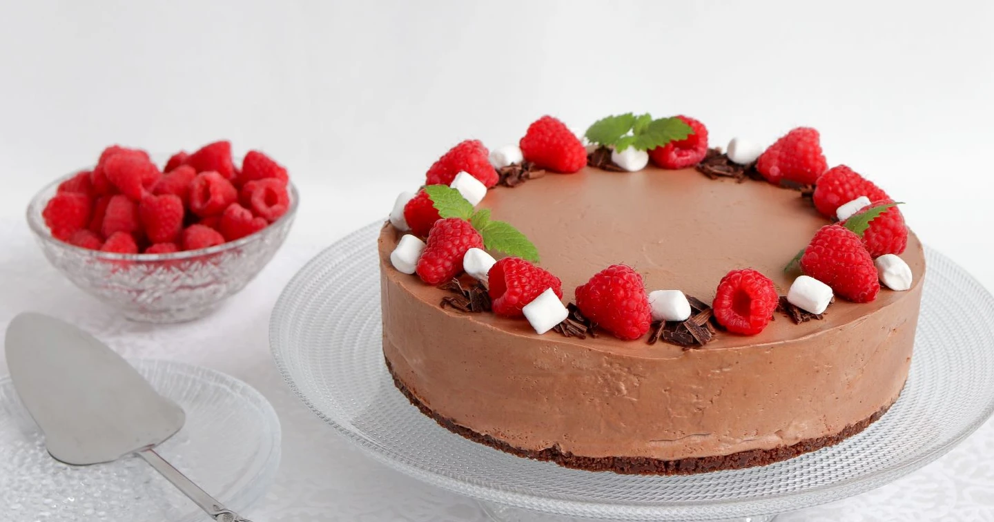 Gluteeniton suklaajuustokakku vadelmilla koristeltuna.