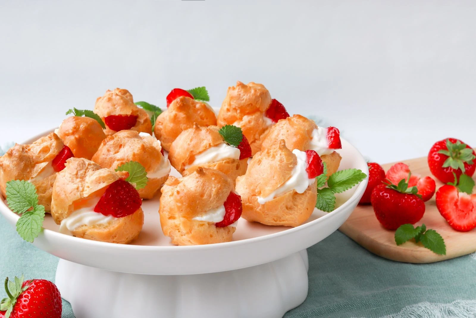 Gluteenittomat tuulihatut, joiden täytteenä on tuoreita mansikoita ja rahkalla maustettua kermaa.