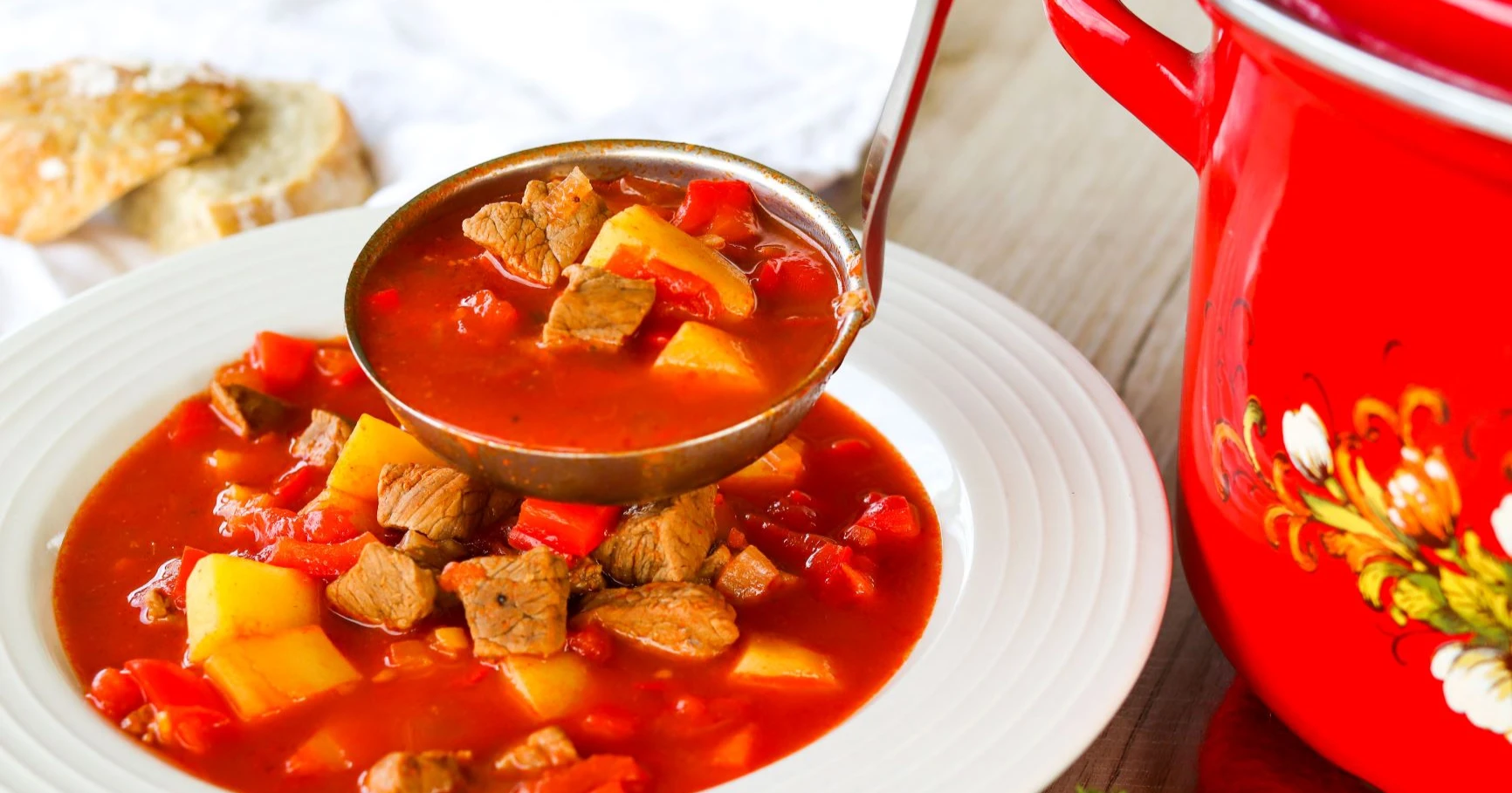 Punaista gulassikeittoa valkoisella lautasella.