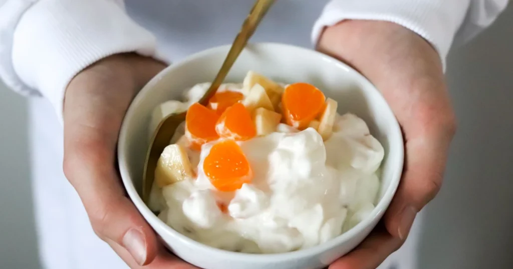 Hedelmillä koristeltu rahka valkoisessa kulhossa.