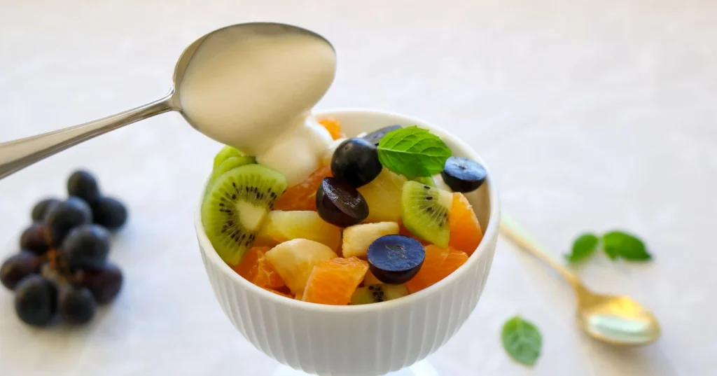 Hedelmäsalaattia kulhossa vaniljavaahdon kera.